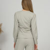 A young woman with blond hair wearing organic cotton blouse with coconut buttons and straight leg trousers in gray color