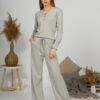 A young woman with blond hair wearing organic cotton blouse with coconut buttons and straight leg trousers in gray color