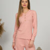 A young woman with blond hair wearing organic cotton blouse with coconut buttons and straight leg trousers in pink color