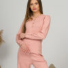 A young woman with blond hair wearing organic cotton blouse with coconut buttons and straight leg trousers in pink color