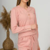 A young woman with blond hair wearing organic cotton blouse with coconut buttons and straight leg trousers in pink color
