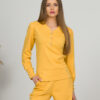A young woman with blond hair wearing organic cotton blouse with coconut buttons and straight leg trousers in yellow color