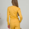A young woman with blond hair wearing organic cotton blouse with coconut buttons and straight leg trousers in yellow color