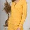 A young woman with blond hair wearing organic cotton blouse with coconut buttons and straight leg trousers in yellow color