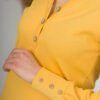 A young woman with blond hair wearing organic cotton blouse with coconut buttons