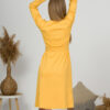 Woman with blond hair wearing organic cotton yellow color long sleeves dress with coconut buttons