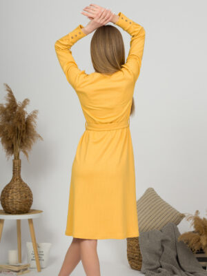 Woman with blond hair wearing organic cotton yellow color long sleeves dress with coconut buttons