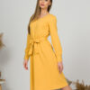Woman with blond hair wearing organic cotton yellow color long sleeves dress with coconut buttons