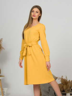 Woman with blond hair wearing organic cotton yellow color long sleeves dress with coconut buttons