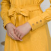 Woman with blond hair wearing organic cotton yellow color long sleeves dress with coconut buttons