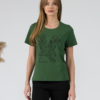 A young woman with blond hair wearing organic cotton green color t-shirt with colored print and black trousers