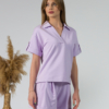 Young woman with blond hair wearing organic cotton violet blouse t-shirt and organic cotton violet shorts
