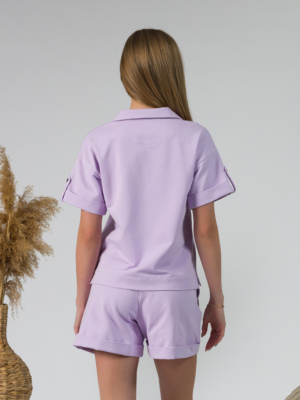 Young woman with blond hair wearing organic cotton violet blouse t-shirt and organic cotton violet shorts