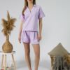 Young woman with blond hair wearing organic cotton violet blouse t-shirt and organic cotton violet shorts