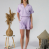 Young woman with blond hair wearing organic cotton violet blouse t-shirt and organic cotton violet shorts