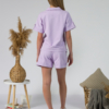 Young woman with blond hair wearing organic cotton violet blouse t-shirt and organic cotton violet shorts