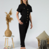 Young woman with blond hair wearing black organic cotton 7/8 length short sleeve jumpsuit with side pockets and coconut buttons