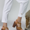 Young woman with blond hair wearing white organic cotton white 7/8 length short sleeve jumpsuit with side pockets and coconut buttons