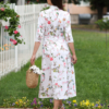 Woman wearing floral organic cotton shirt dress with bracelet sleeves coconut buttons and waist belt