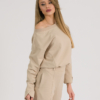 woman with blond hair wearing beige organic cotton long sleeve off shoulder boat neck blouse and beige organic cotton long tapered leg pants