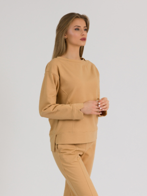 woman with blond hair wearing brown organic cotton long sleeve off shoulder boat neck blouse and brown organic cotton long tapered leg pants