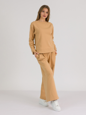 woman with blond hair wearing brown organic cotton long sleeve off shoulder boat neck blouse and brown organic cotton long wide legs pants