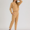 woman with blond hair wearing brown organic cotton long sleeve off shoulder boat neck blouse and brown organic cotton long tapered leg pants