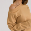 woman with blond hair wearing brown organic cotton long sleeve off shoulder boat neck blouse and brown organic cotton long tapered leg pants