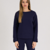 woman with blond hair wearing dark blue organic cotton long sleeve off shoulder boat neck blouse and dark blue organic cotton long tapered leg pants