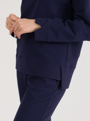 woman with blond hair wearing dark blue organic cotton long sleeve off shoulder boat neck blouse and dark blue organic cotton long tapered leg pants