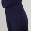 woman with blond hair wearing dark blue organic cotton oversized polo collar sweatshirt and dark blue organic cotton long tapered leg pants