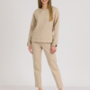 woman with blond hair wearing beige organic cotton elegant blouse and beige organic cotton long tapered leg pants