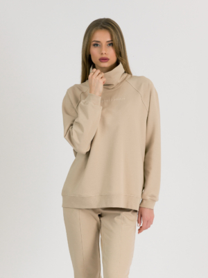 woman with blond hair wearing beige organic cotton oversized polo collar sweatshirt and beige organic cotton long tapered leg pants