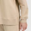 woman with blond hair wearing beige organic cotton oversized polo collar sweatshirt and beige organic cotton long wide pants