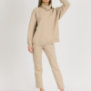 woman with blond hair wearing beige organic cotton oversized polo collar sweatshirt and beige organic cotton long tapered leg pants