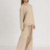 woman with blond hair wearing beige organic cotton oversized polo collar sweatshirt and beige organic cotton long wide pants