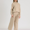 woman with blond hair wearing beige organic cotton oversized polo collar sweatshirt and beige organic cotton long wide pants