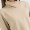 woman with blond hair wearing beige organic cotton oversized polo collar sweatshirt and beige organic cotton long wide pants