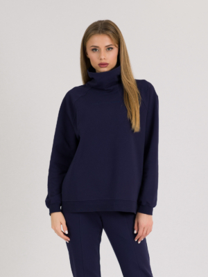 woman with blond hair wearing dark blue organic cotton oversized polo collar sweatshirt and dark blue organic cotton long tapered leg pants