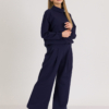 woman with blond hair wearing dark blue organic cotton oversized polo collar sweatshirt and dark blue organic cotton long wide pants