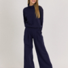 woman with blond hair wearing dark blue organic cotton oversized polo collar sweatshirt and dark blue organic cotton long wide pants
