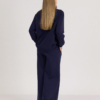 woman with blond hair wearing dark blue organic cotton oversized polo collar sweatshirt and dark blue organic cotton long wide pants