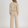 Woman with blond hair wearing beige organic cotton blouse and beige long wide pants