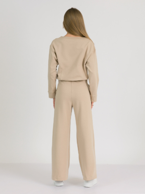 Woman with blond hair wearing beige organic cotton blouse and beige long wide pants