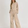 Woman with blond hair wearing beige organic cotton blouse and beige long wide pants