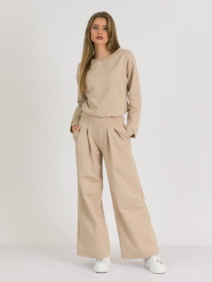 Woman with blond hair wearing beige organic cotton blouse and beige long wide pants