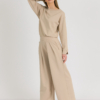 Woman with blond hair wearing beige organic cotton blouse and beige long wide pants