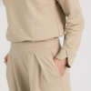 Woman with blond hair wearing beige organic cotton blouse and beige long wide pants