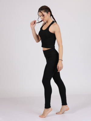 Women with brown hair is wearing black organic cotton tank top and black organic cotton leggings