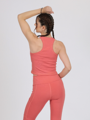 Women with brown hair is wearing pink organic cotton tank top and pink organic cotton leggings